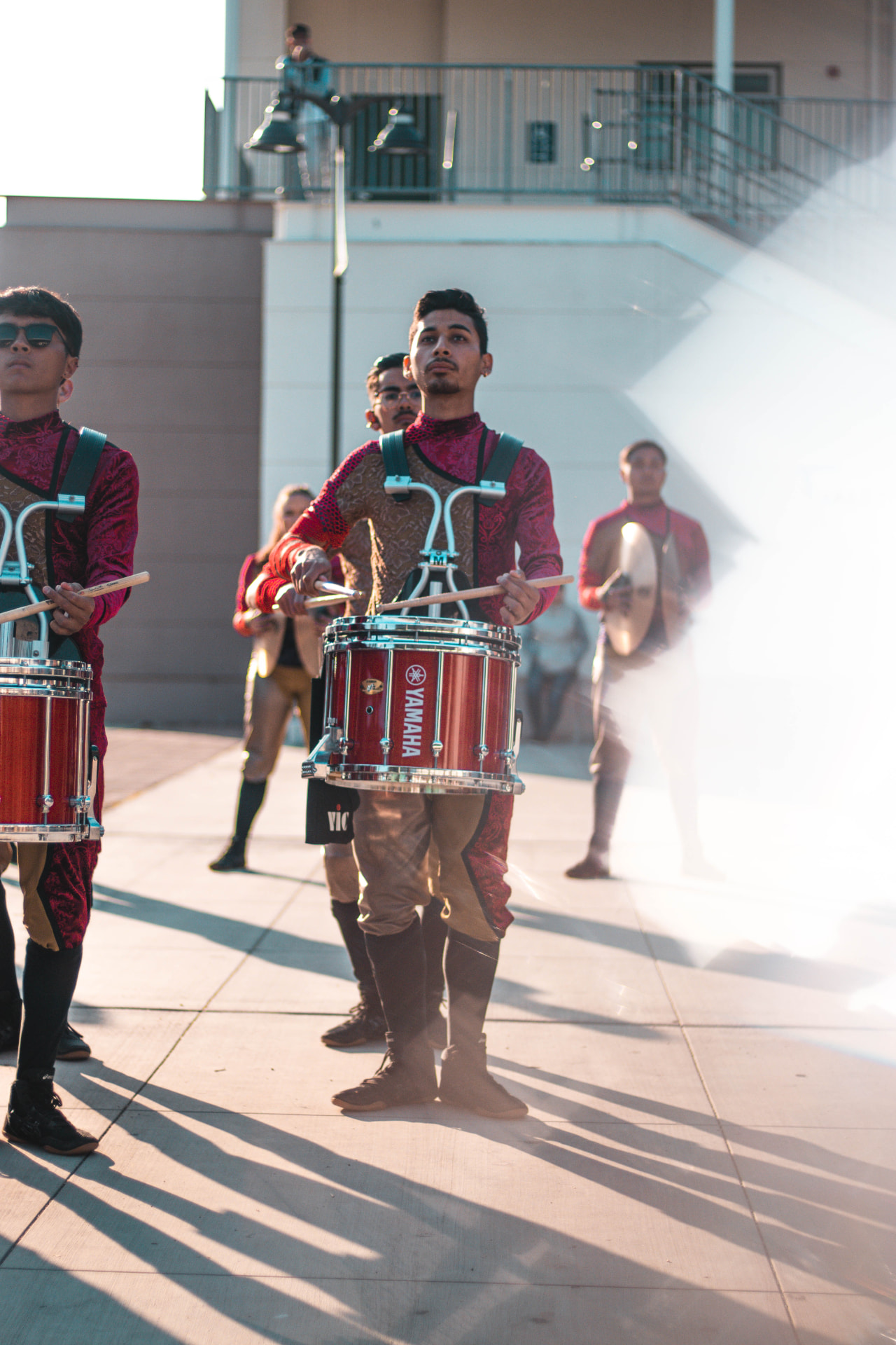 Marching snare drummer in a red and gold uniform on the practice field